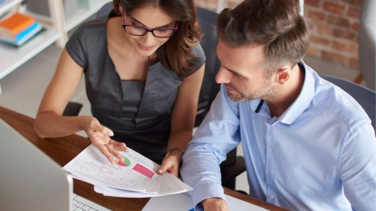 Um homem e uma mulher conversando e analisando relatórios